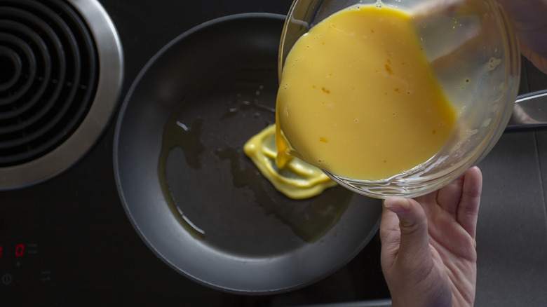 Person pouring eggs into a pan