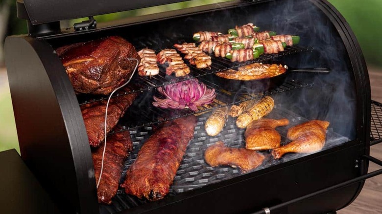 An open Oklahoma Joes grill cooking meats and veggies