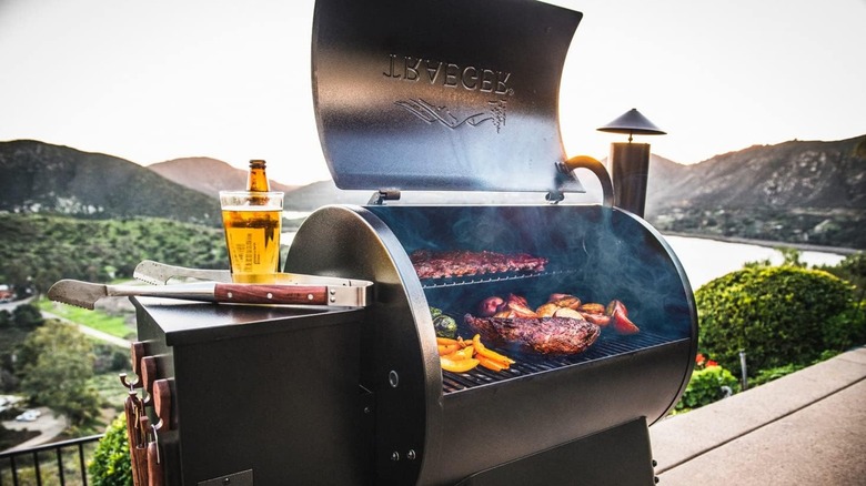 An open Traeger grill cooking meats and veggies