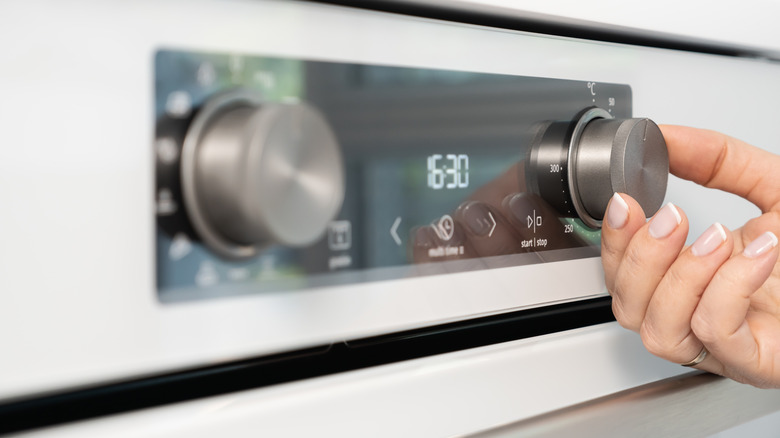 A person adjusting the oven temperature