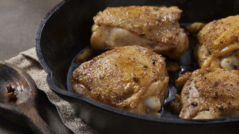 Chicken thighs cooking in a pan with fat