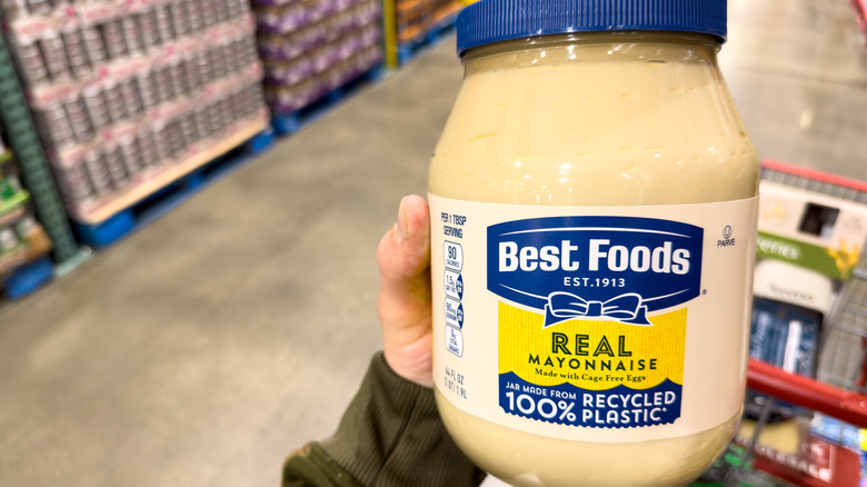 person's hand holding a large jar of mayo from costco