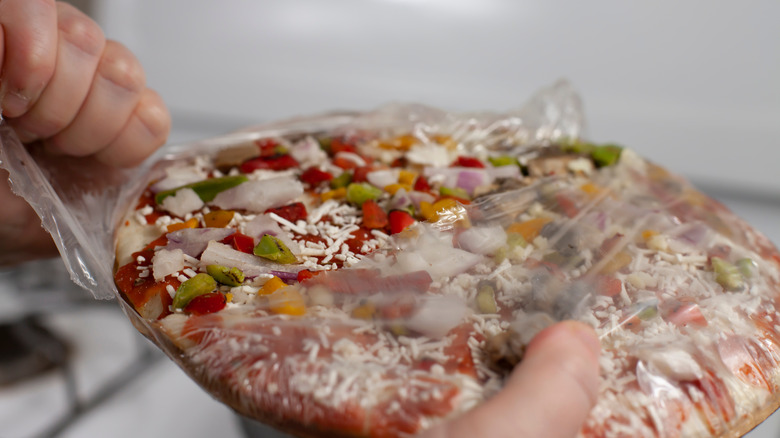 Person unwrapping a take-and-bake pizza