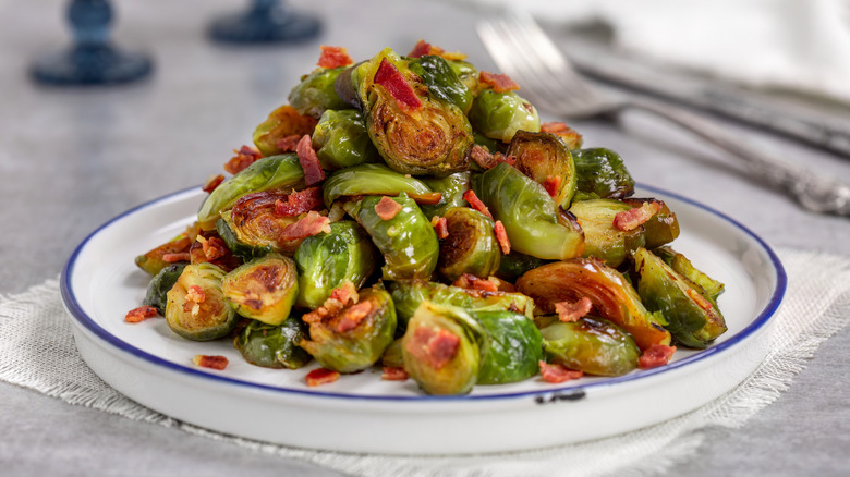 a dish of halved and cooked Brussels sprouts with bacon bits