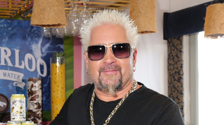 TV chef Guy Fieri wearing a black t shirt and a heavy gold necklace