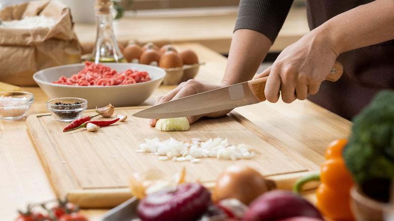 close up of someone chopping onions on a wooden chopping board