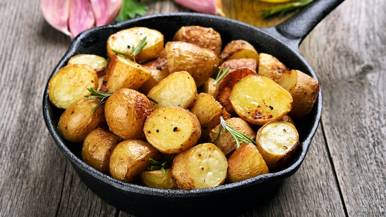 sautéd potatoes in a cast iron black skillet, on a wooden table