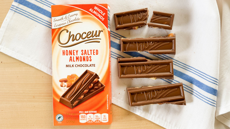 Choceur Honey Salted Almonds Milk Chocolate bar broken into pieces with packaging on table