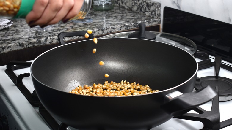 pouring popcorn kernels into pan