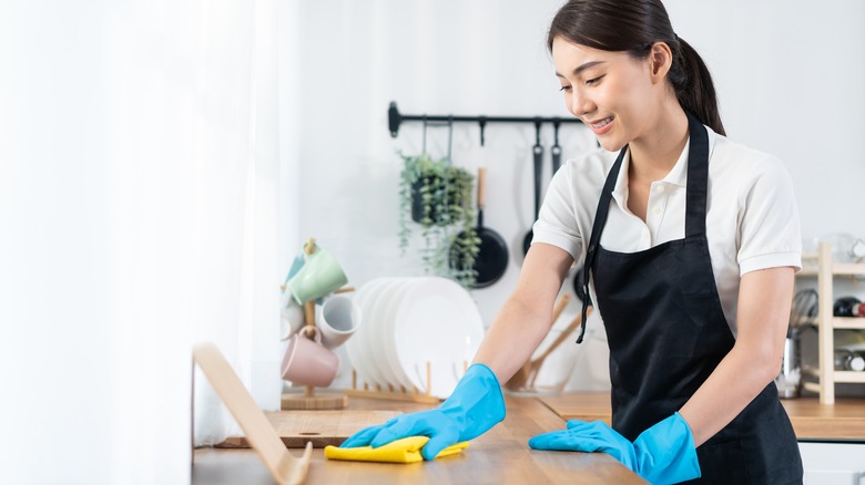 A woman cleaning in an apron and gloves