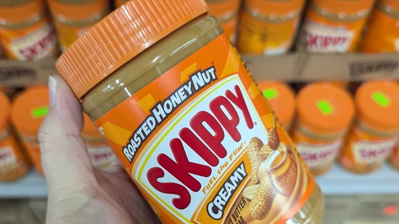 hand holding jar of Skippy Roasted Honey Nut Creamy Peanut Butter Spread