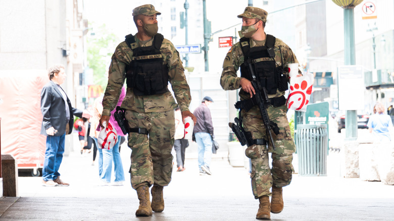 Two soldiers carrying Chick-fil-A bag while walking on the street