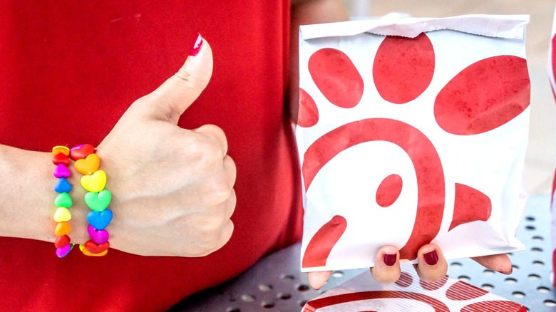 A person giving thumbs up with Chick-fil-A bag