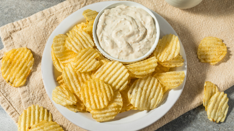 A plate of potato chips with a bowl of dip