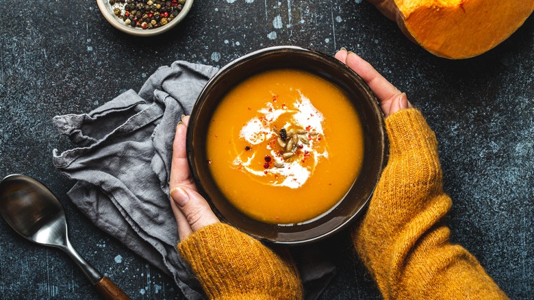 Hands holding bowl of pumpkin soup