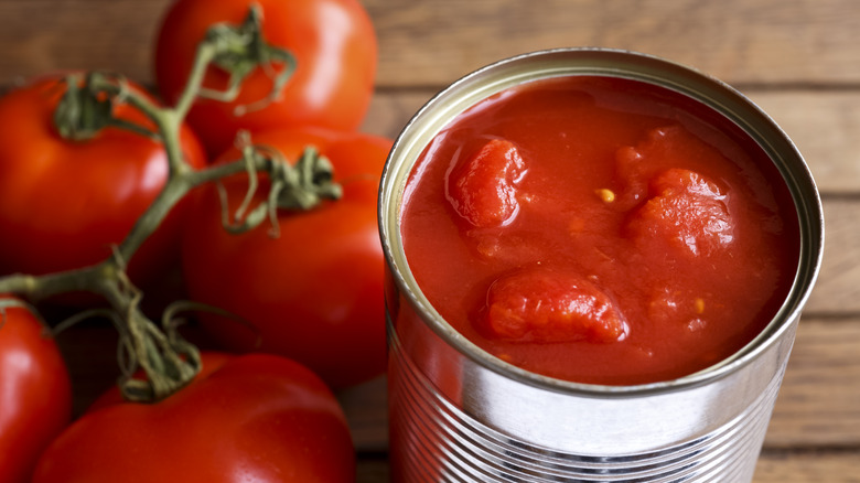 canned tomatoes with fresh tomatoes on table