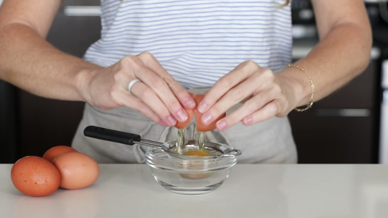 Woman cracking an egg into a sieve