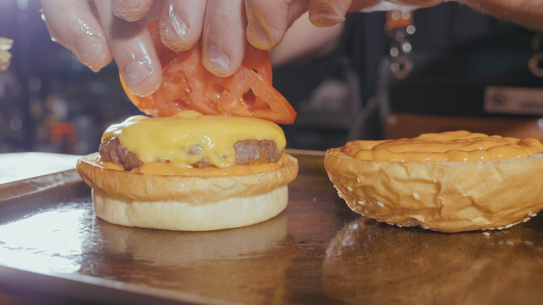 hands assembling cheeseburger