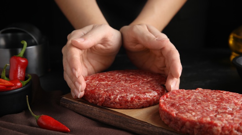 hands holding raw hamburger patty