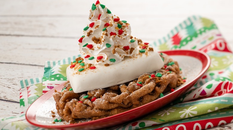 Funnel cake with holiday sprinkles and whipped cream.