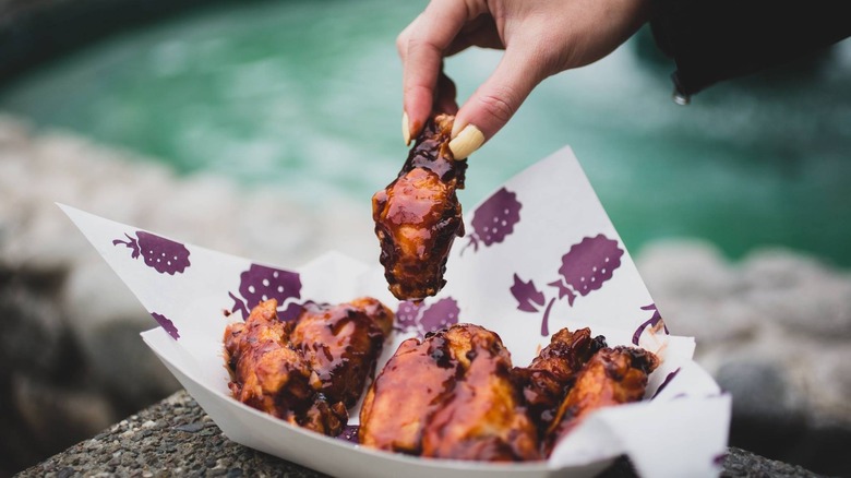 Hand plucking a chicken wing from a basket of chicken wings