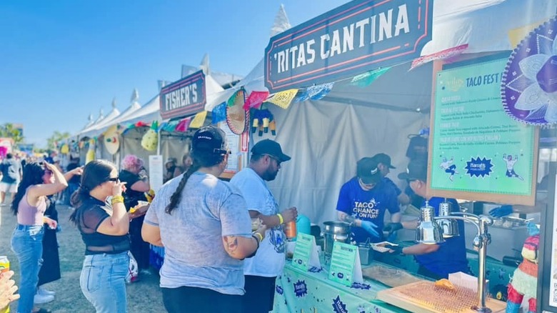 people lining up to get tacos from a food truck