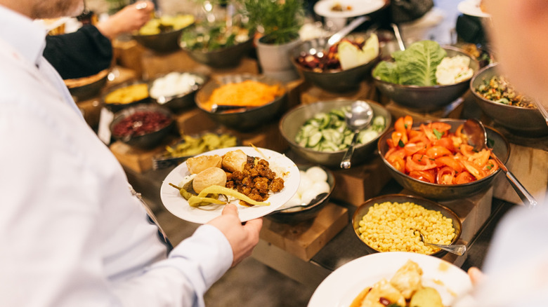 people loading plates with food at a buffet