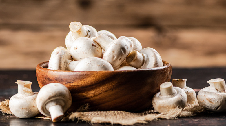 A wooden bowl of white button mushrooms