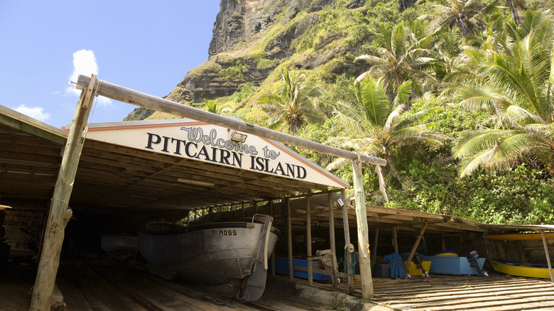 a boat in a wooden building with a sign reading Welcome to Pitcairn Island