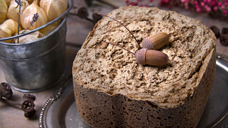 A square loaf of artisanal bread with two acorns on top