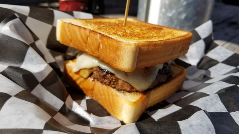 a burger between two slices of Texas toast, on a black and white checkered serviette