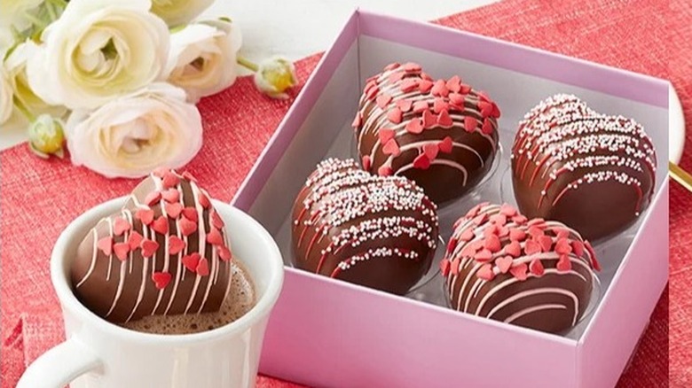 A box of Harry & David's heart-shaped Hot Cocoa Bombs with one chocolate in a cup