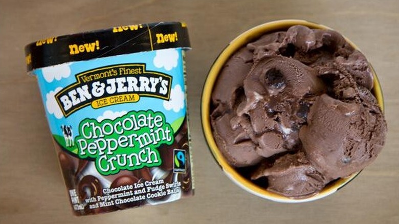 A top-down view of a tub of Ben & Jerry's chocolate peppermint crunch ice cream, next to a bowl of it