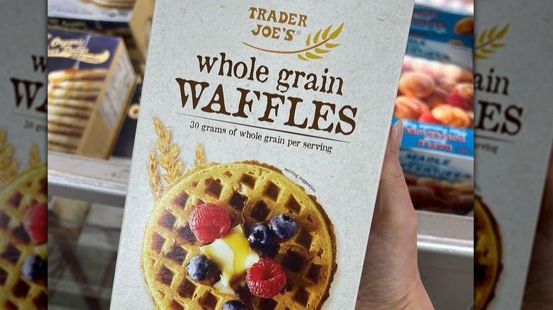 A hand holding a box of Trader Joe's Multi Grain Waffles