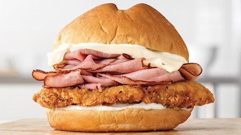 A close-up of an Arby's Chicken Cordon Bleu sandwich on a wooden table