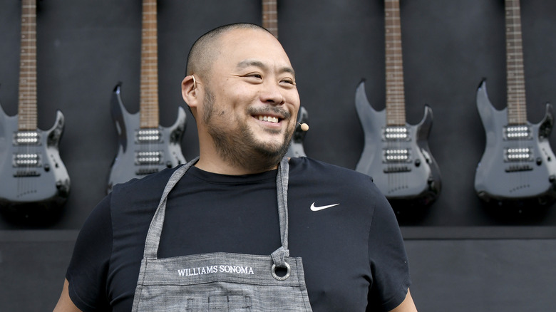 David Chang smiling in front of a wall of electric guitars