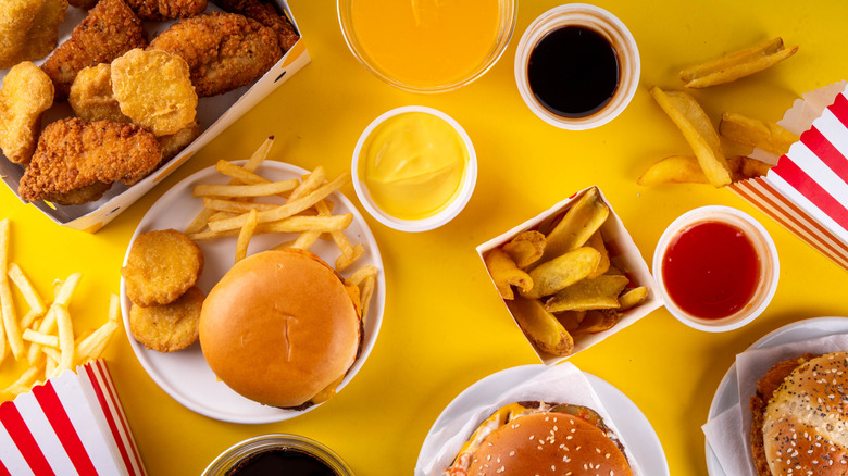 Fast food delivery menu background with various burgers, cheeseburger, nuggets, french fries, fizzy soda drinks. Junk unhealthy fast food,       <span class=