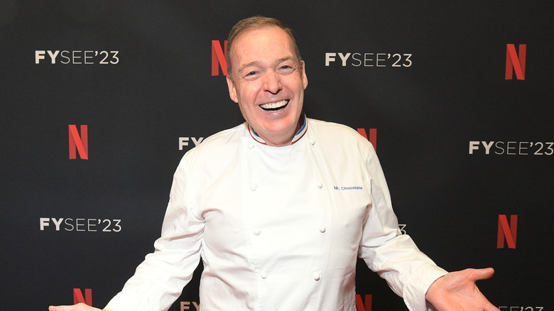 Jacques Torres smiling in front of a step and repeat