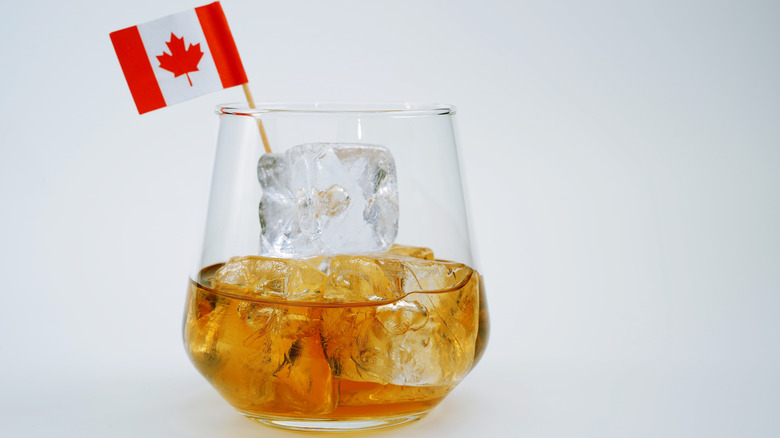 Whiskey on the rocks with Canadian flag on stick, white background