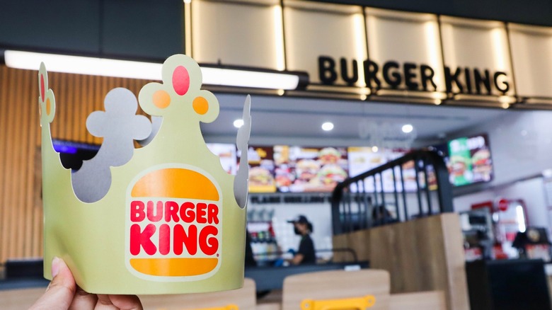 Person holding Burger King paper crown in restaurant