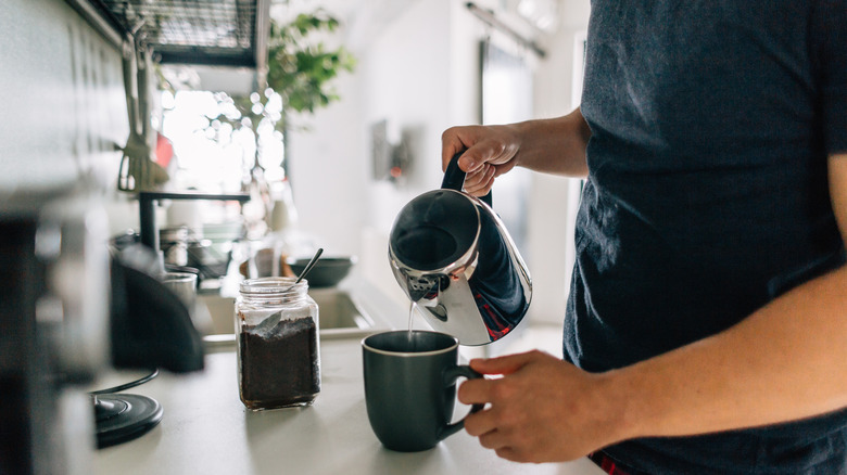 A man pouring a cup of coffee in the kitchen