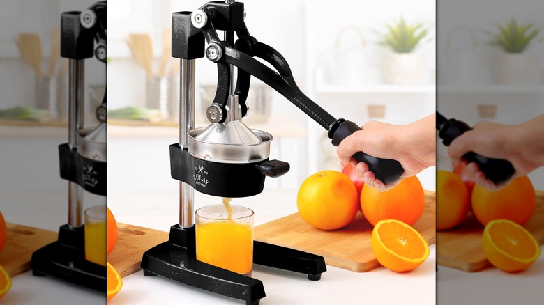 A person squeezing an orange with a Zulay juicer