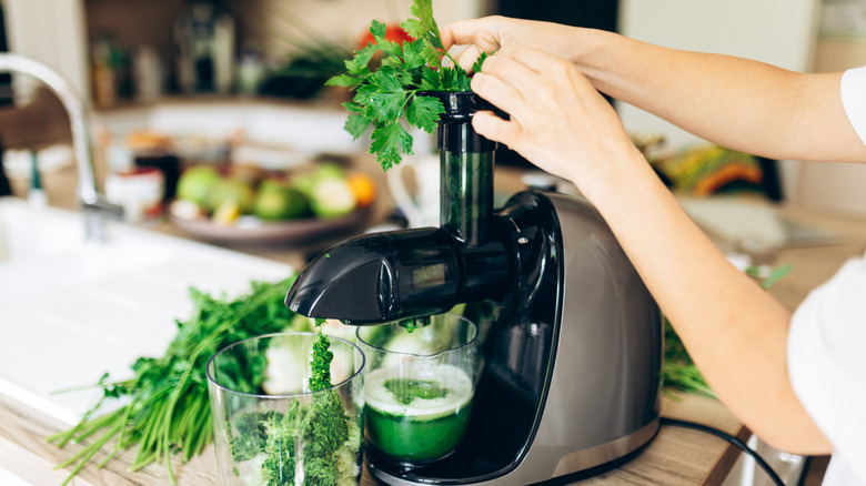 A person loading veggies into a juicer