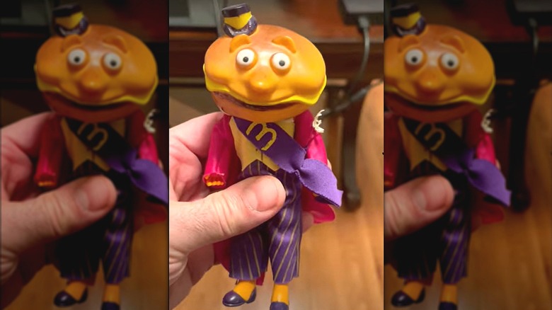 A hand holding Mayor McCheese up to the camera