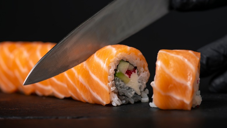Knife slicing a sushi roll