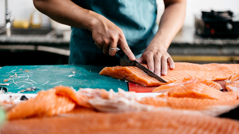 Person preparing salmon for sushi