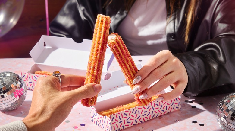 Two people holding Milk Bar Birthday Cake Churros closeup