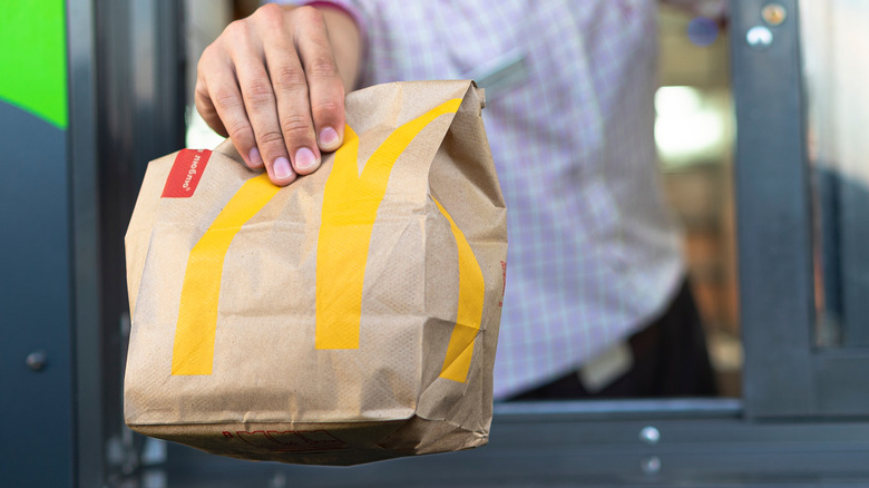 Person passing McDonald's bag through drive-thru window