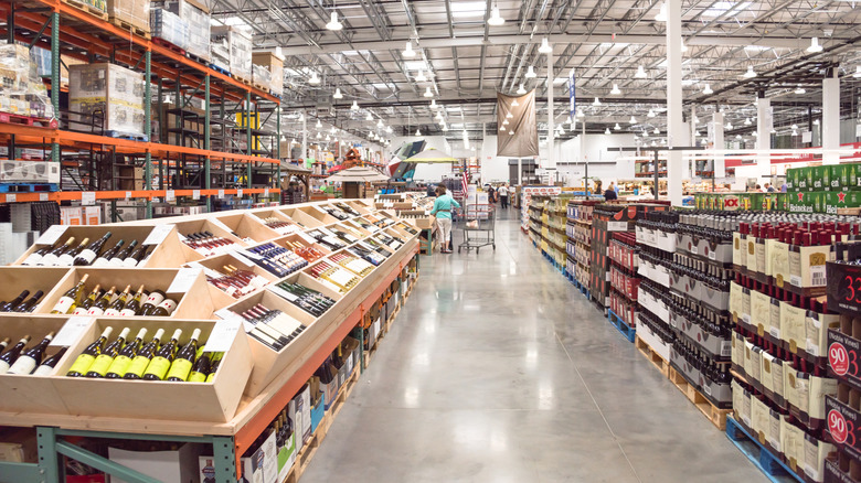 Costco customer with cart shopping in liquor section of store.