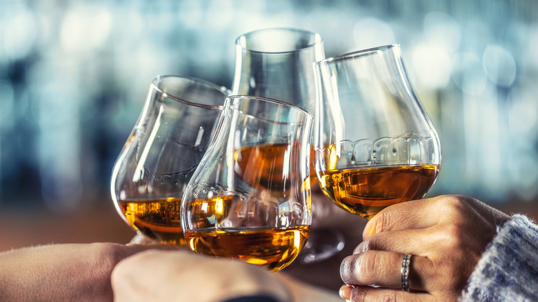 Closeup of hands toasting with snifter glasses of Cognac.